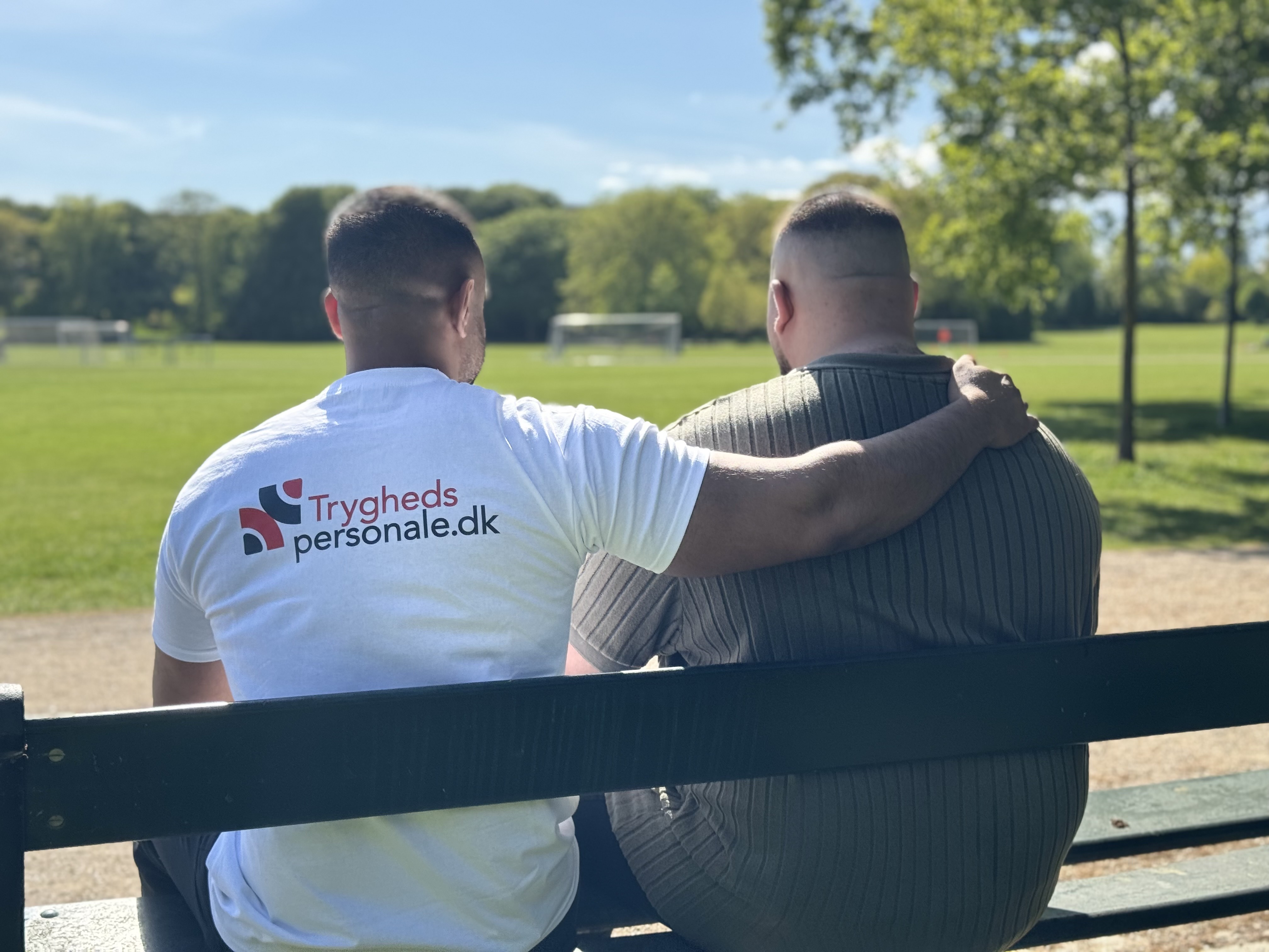 Tryghedspersonale sidder på en bænk udenfor med beboer